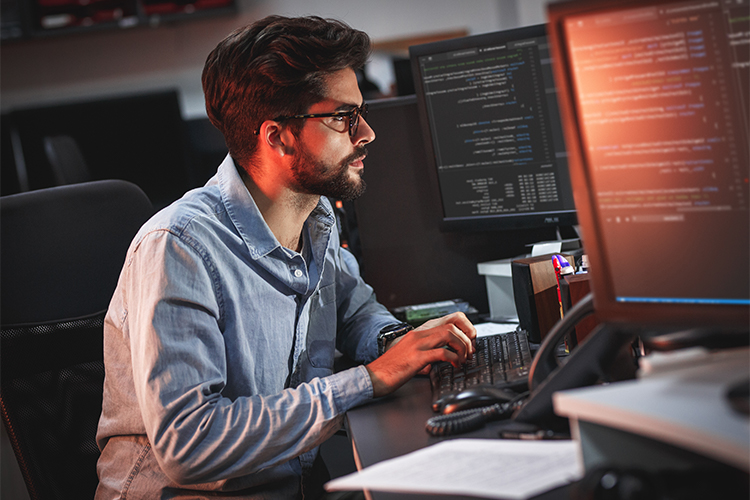 Ein Mann sitzt an einem Computer und arbeitet an etwas.